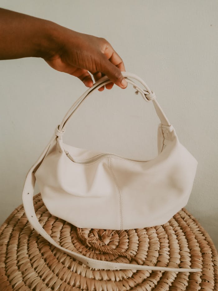 Elegant white handbag held by hand, showcasing minimalist design and fashion.