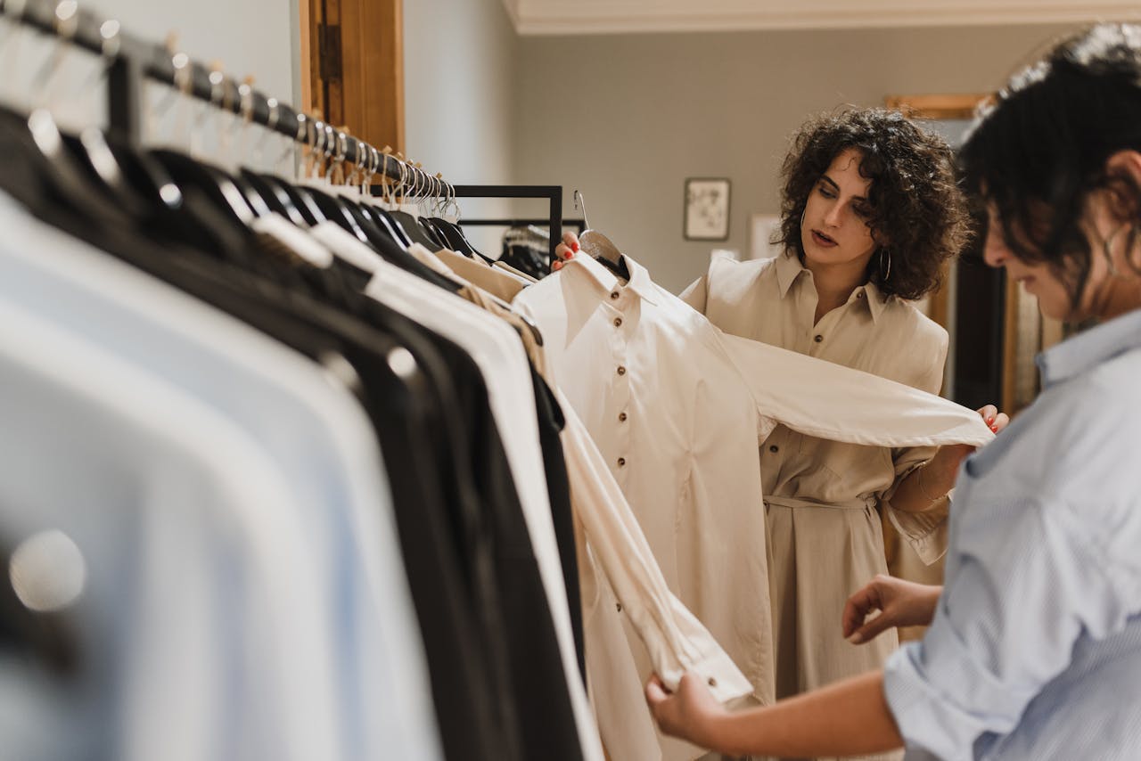 Two women carefully selecting clothes from a rack in a stylish boutique.