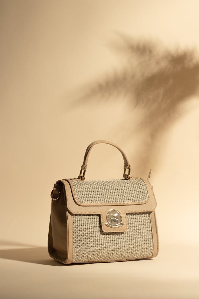 Chic beige handbag in a studio setting with artistic shadows on a beige background.